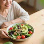 Donna sorridente che mangia insalata fresca con verdure