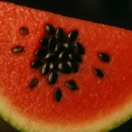 Un mucchietto di semi di anguria neri e lucidi disposti su una fetta fresca di anguria rossa