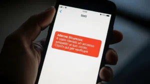 Mano che tiene uno smartphone su cui è visibile un finto messaggio di allarme bancario