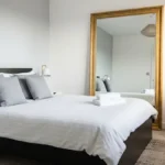 Una camera da letto elegante con un grande specchio antico di fronte al letto