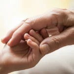 la mano di una persona anziana che stringe quella di un bambino