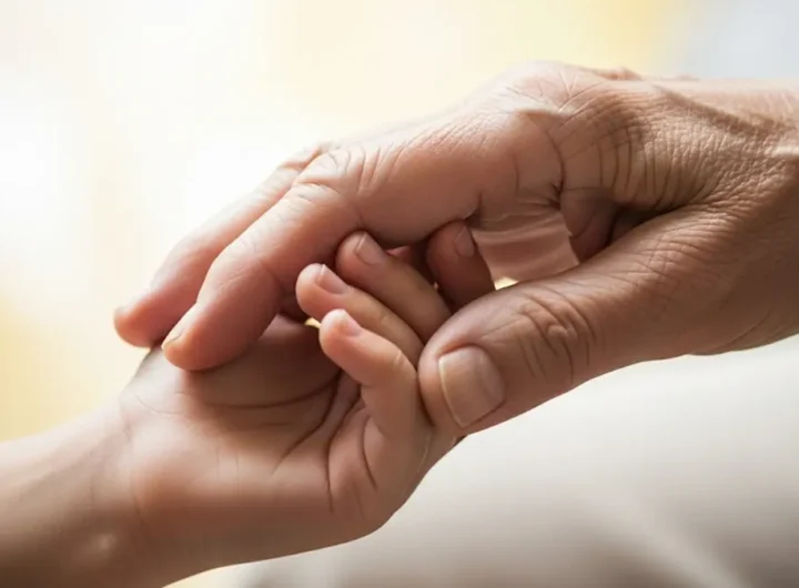 la mano di una persona anziana che stringe quella di un bambino