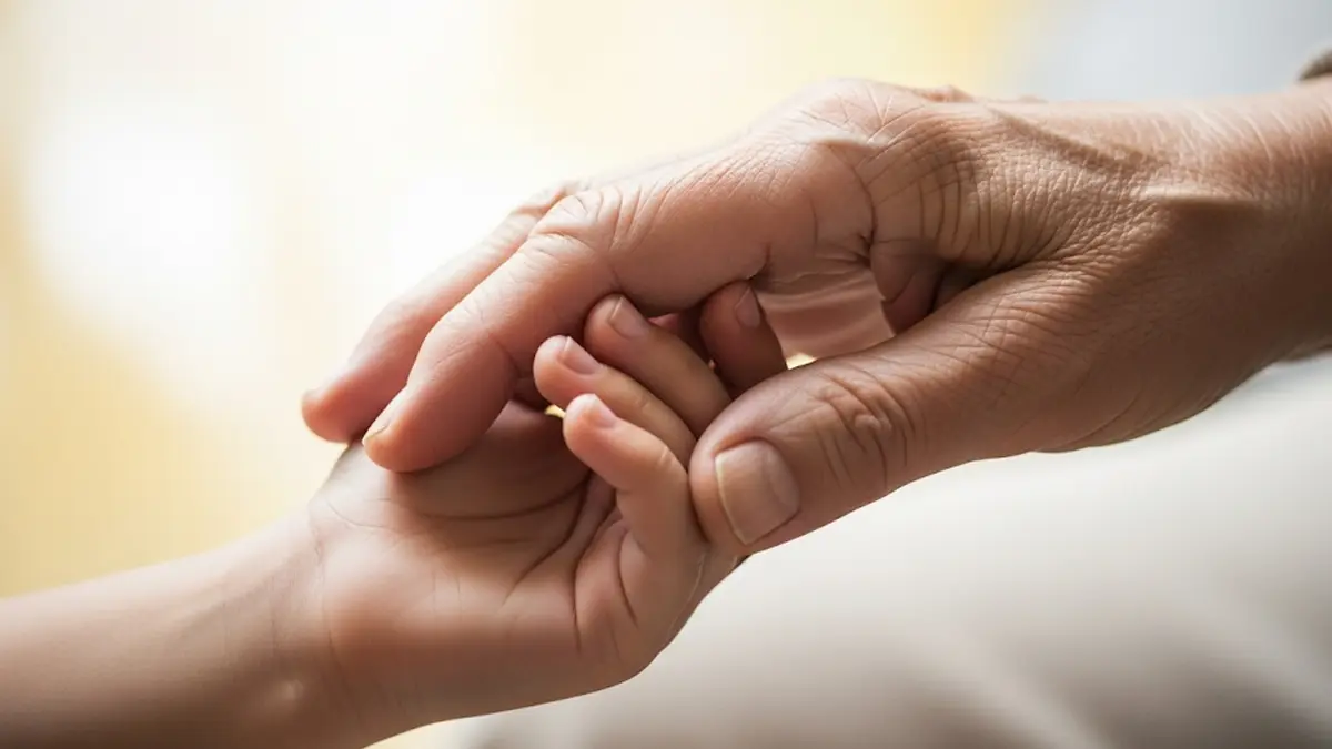 la mano di una persona anziana che stringe quella di un bambino