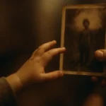 Bambino piccolo che guarda con curiosità una vecchia fotografia in bianco e nero