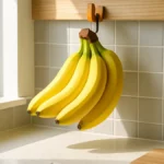 Un casco di banane gialle appeso a un gancio in una cucina luminosa