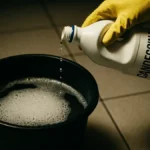 Flacone di candeggina e straccio su un pavimento in piastrelle pulito