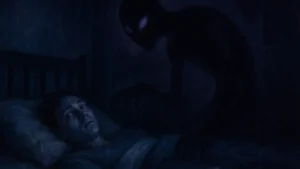 Primo piano di un volto parzialmente illuminato che giace a letto con espressione di lieve ansia