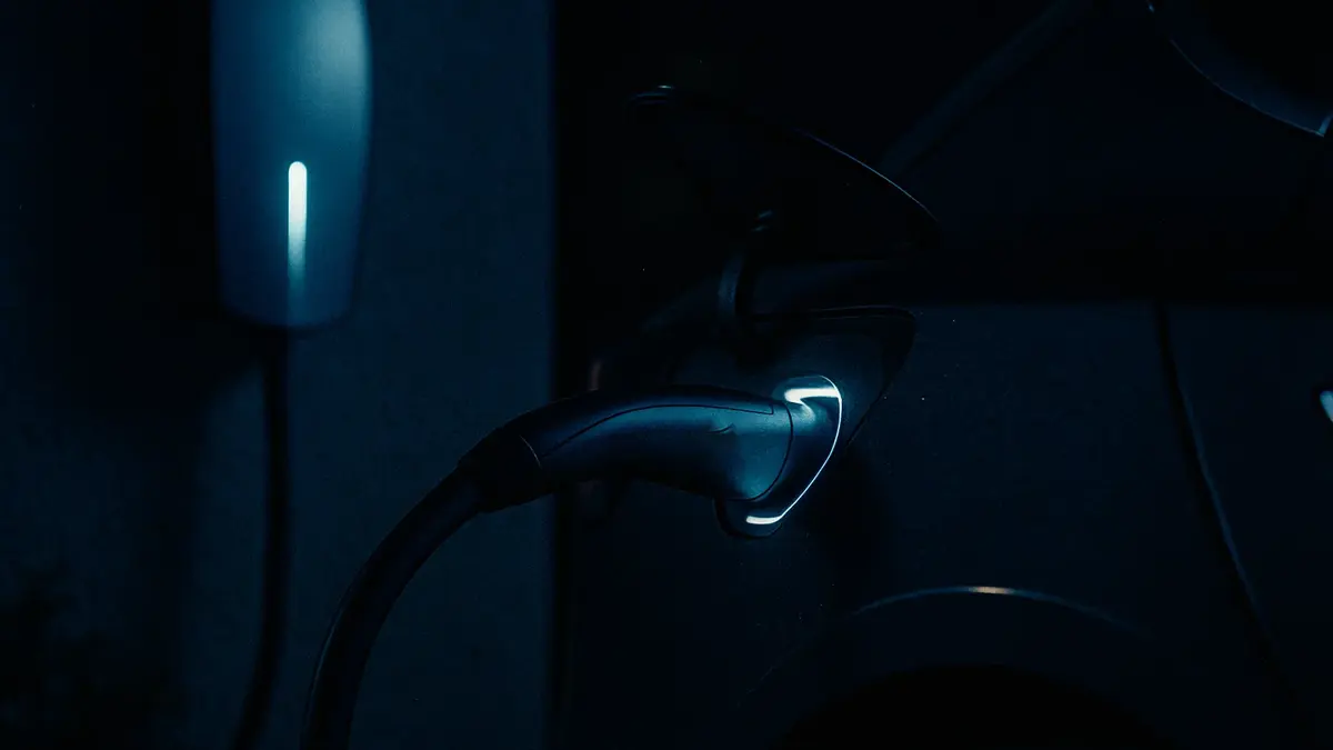 Uomo che ricarica un'auto Tesla di notte a casa con uno sfondo sfocato